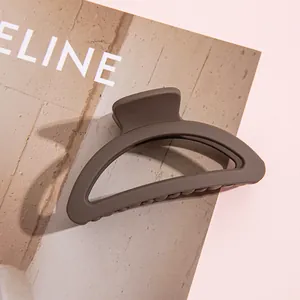 Gros plan d'une pince à cheveux mate taupe posée sur un magazine de style de vie