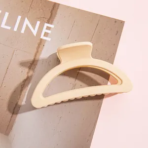 Gros plan d'une pince à cheveux mate crème au design arrondi posée sur un magazine mode