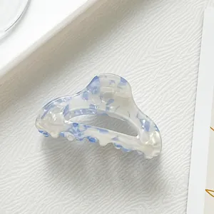 Dettaglio della molletta per capelli in acetato marmorizzato blu con trama elegante