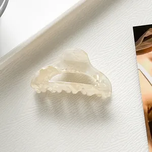 Dettaglio ravvicinato di una piccola molletta per capelli in acetato marmorizzato bianco