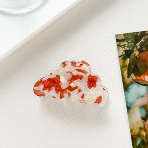 Dettaglio di un fermaglio per capelli in acetato a fiori rossi a forma di nuvola bianca