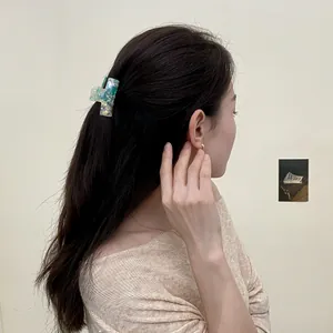 Molla per capelli in acetato marmorizzato verde e bianco su acconciatura semi-raccolta