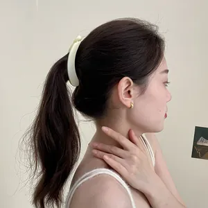 Large matte cream banana hair clip securing a thick ponytail for women on plain background
