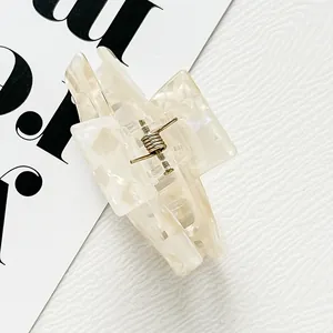 Elegant cream marble acetate hair claw clip with golden spring on a minimalist background