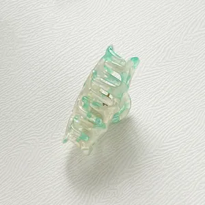 Macro view of mint green marble acetate hair claw clip with metallic spring detail