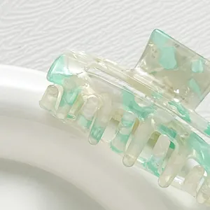 Macro detail of rectangle acetate hair claw with mint green marble texture and metal spring