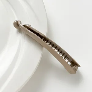 Glossy apricot banana clip with dual-row teeth on white porcelain plate detail