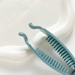 Blue-grey banana hair clip with non-slip teeth for thick hair shown on a white plate