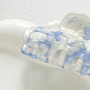 Macro detail of acetate hair claw clip featuring icy blue marble texture and pearl finish