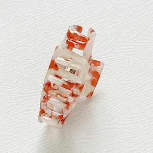 Detailed close-up of orange marble acetate hair claw clip with sturdy metal spring