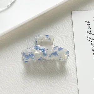 Vue détaillée d'une pince à cheveux en acétate blanc avec motifs floraux bleus et nacrés