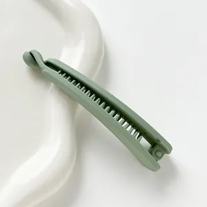 Macro detail of large matte green banana hair clip on a white decorative plate
