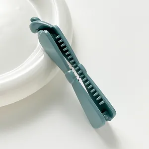 Detail of blue matte banana hair clip with secure inner teeth on a ceramic plate