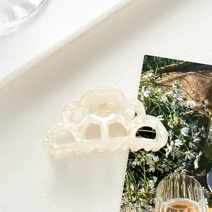 Detail of cream white acetate hair claw clip with pearl luster and cloud edge design