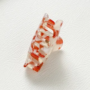 Detailansicht der kleinen Blumen-Haarklammer mit orangefarbenem Marmormuster und Metallfeder