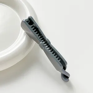 Détail de la pince à cheveux banane grise avec dents de fixation sur un plat blanc
