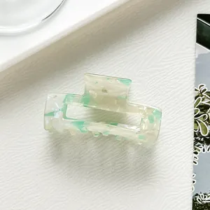 Detail of rectangular acetate hair claw with mint green and cream marble texture