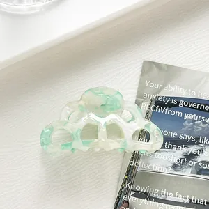 Detail of light green marble acetate hair claw clip with cloud wave hollow design