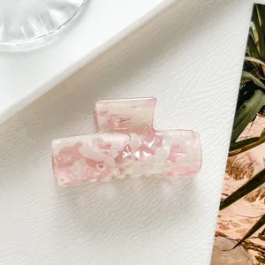 Dettaglio macro di una pinza per capelli in acetato marmorizzato rosa con molla