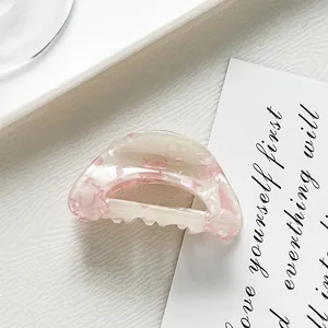 Detailed close-up of semi-circle acetate hair claw clip with pink shell texture and teeth