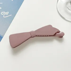 Detail of glossy dusty pink banana hair clip with a stylish bow-knot design