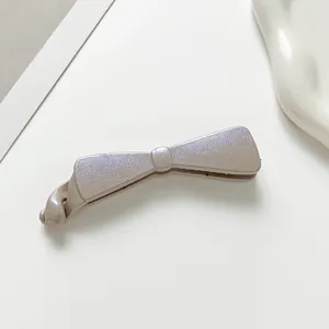 Détail d'une grande pince banane nœud gris avec fini nacré et dents antidérapantes