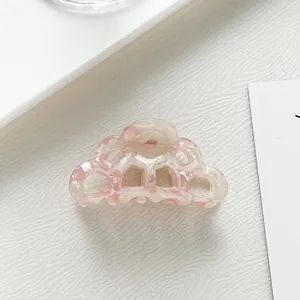 Macro detail of wave-shaped pink and cream acetate hair claw clip with marble texture