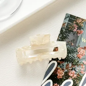 Macro view of a rectangular cream marble acetate hair claw clip with a strong metal spring