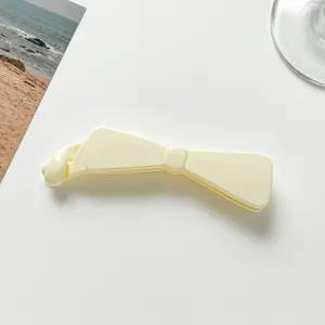 Detail view of the elegant cream-colored bow banana hair clip with smooth resin finish