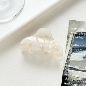 Details einer cremefarbenen Acetat-Haarklammer mit Marmortextur auf dezentem Hintergrund