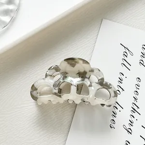 Detail view of acetate hair claw clip with grey and white marble pattern on white desk