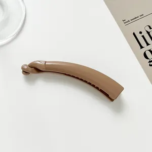 Macro shot of glossy brown banana hair clip with internal teeth on minimalist background