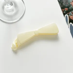 Détail macro d'une pince à cheveux nœud crème avec finition mate sur fond blanc
