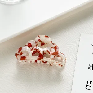 Detailed texture of acetate hair claw clip with tortoise marble pattern on white surface