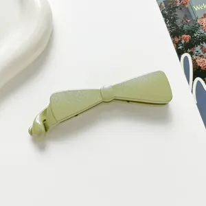 Détail de la pince banane vert clair avec finition pailletée et design en nœud