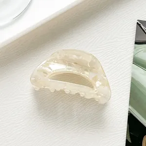 Detailed view of a semi-circular acetate hair claw clip with cream marble texture