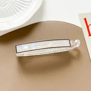 Detail of a large pearlescent banana hair clip with transparent teeth on leather
