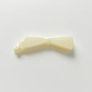Détail de la pince banane crème nacrée avec design en nœud pour cheveux épais