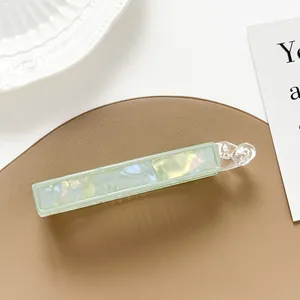 Detail of banana hair clip with light green pearlescent acrylic texture on leather