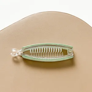 Close-up of a light green translucent banana clip showing the inner comb teeth design