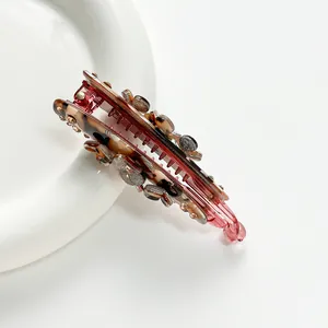 Macro detail of red translucent banana hair clip with leopard print and glitter details