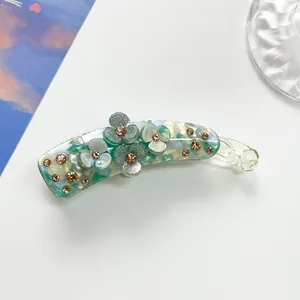 Detailed view of banana hair clip with three-petal flowers and sparkling rhinestones