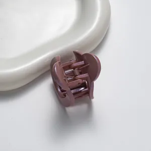 Detail of dusty pink matte hair claw clip with subtle glitter finish on a white tray