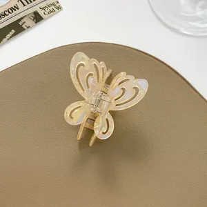 Close-up of hollow butterfly hair claw with pearlescent finish on premium leather background