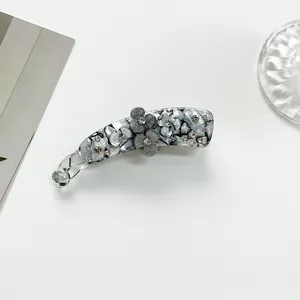 Detail view of marble pattern banana clip with 3D floral accent and rhinestones