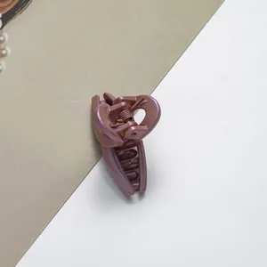 Gros plan d'une pince à cheveux rose poudré nacrée avec finition pailletée sur fond blanc