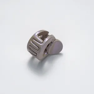 Macro shot of small glittery champagne hair claw clip with interlocking teeth and pearl finish