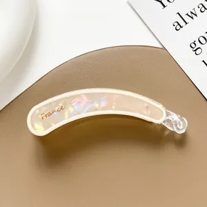 Detalle de pinza banana rosa perlada con logotipo France grabado y textura de nácar