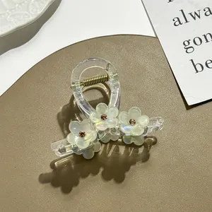 Detail van transparante acryl haarklem met parelmoer bloemen en strass steentjes