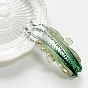 Barrette banane élégante verte translucide avec cristaux sur assiette céramique
